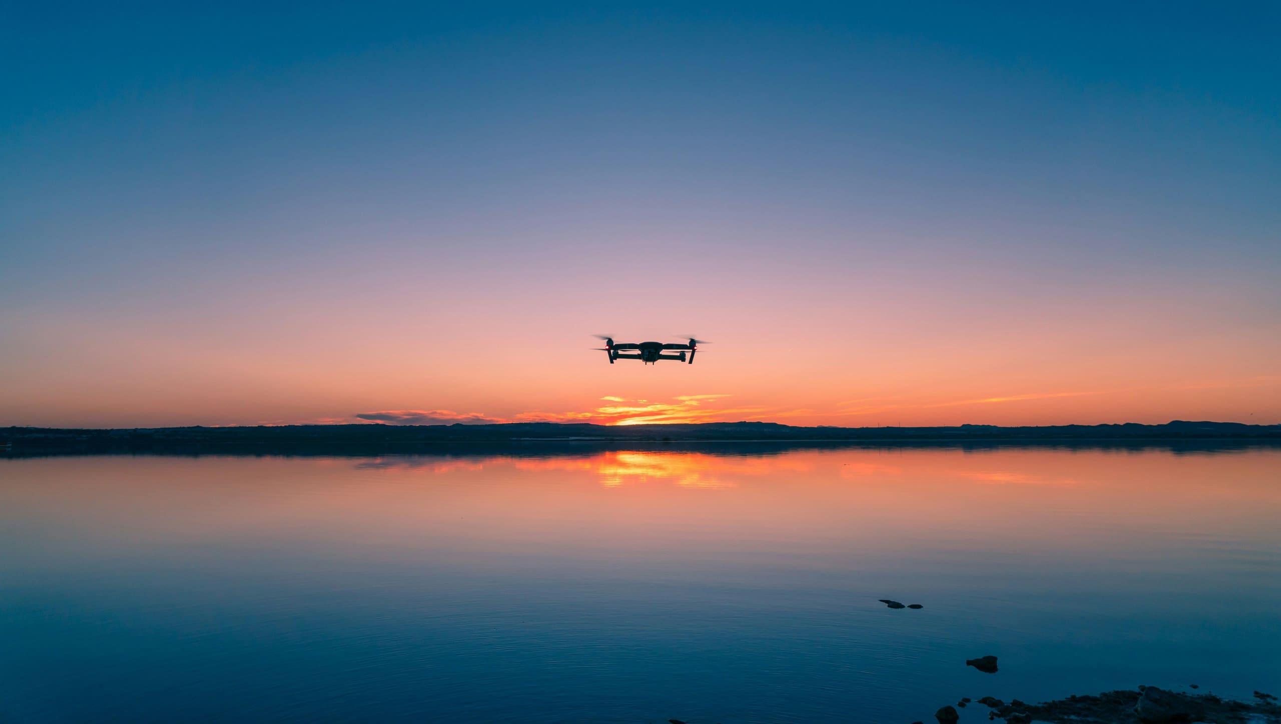 Drone en vol au crépuscule au-dessus d'un lac immobile