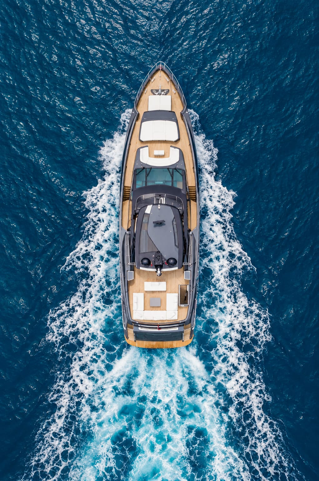 Yacht à moteur vu du ciel, sillage blanc sur une mer bleu profond